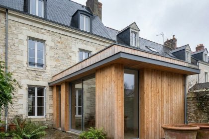 Extension en bois moderne accolée à une maison de ville nantaise, vue depuis le jardin avec contraste entre pierre ancienne et bardage en douglas naturel